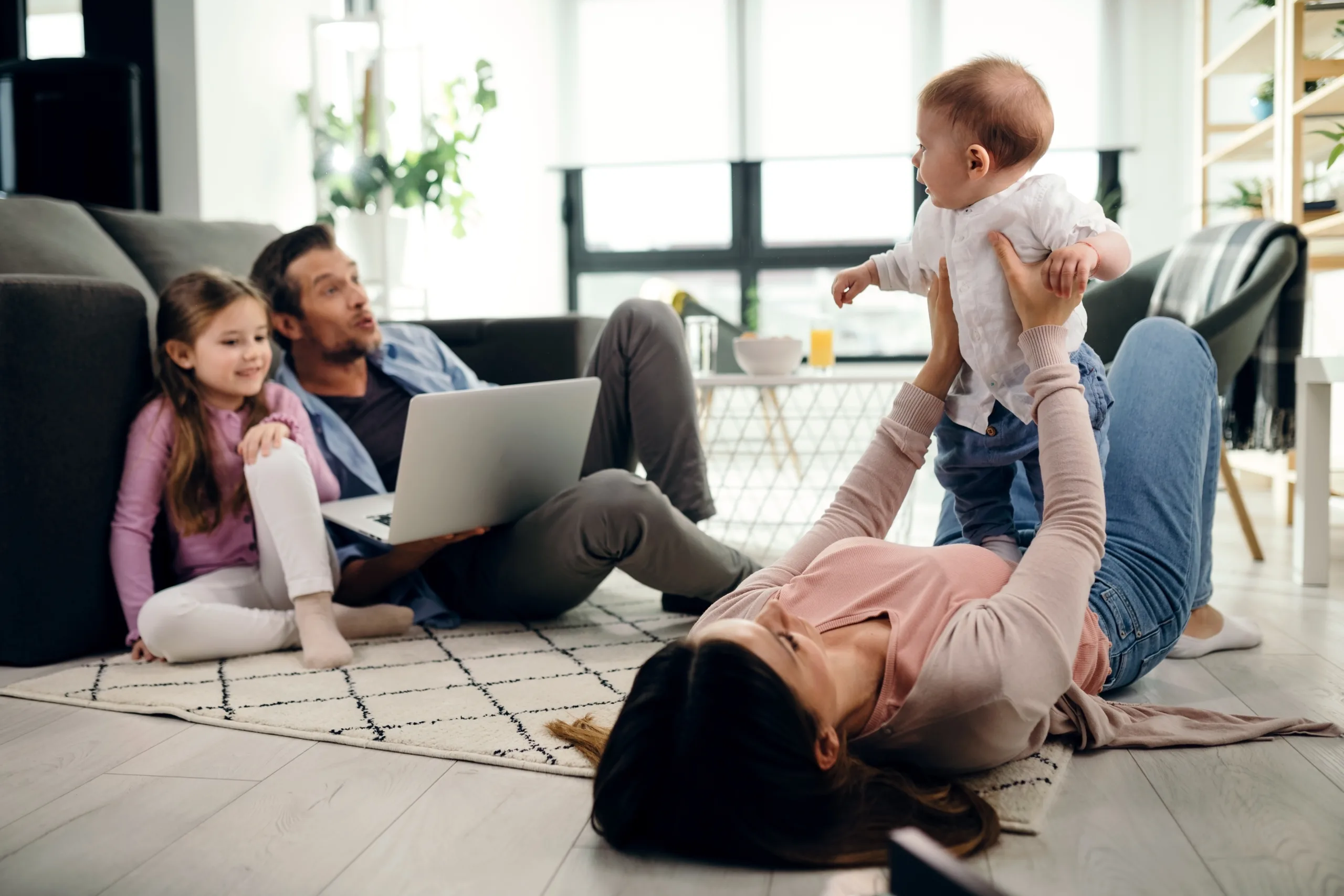 madre-juguetona-sosteniendo-su-hijo-mientras-esta-acostado-en-el-suelo-en-la-sala-de-estar-padre-e-h
